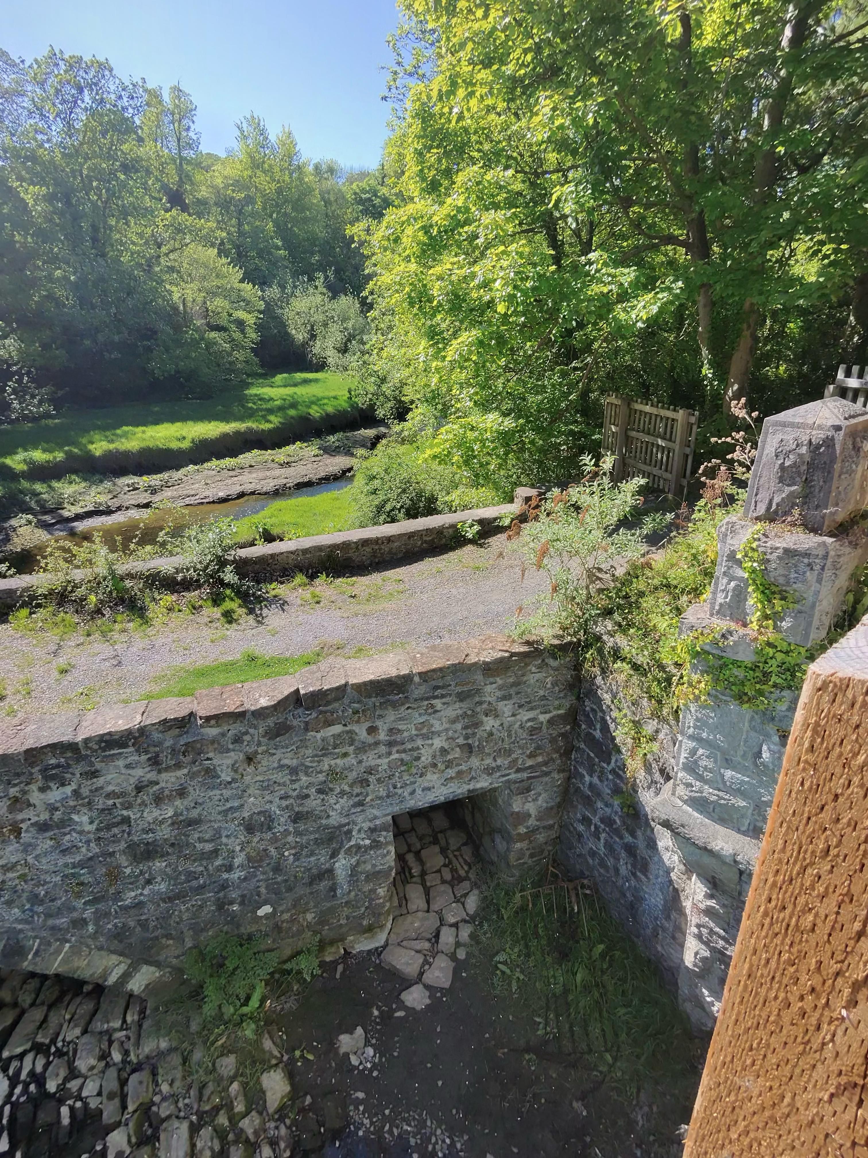 Ancient stone bridge over the Afon Ogwen, surrounded by summer woodland