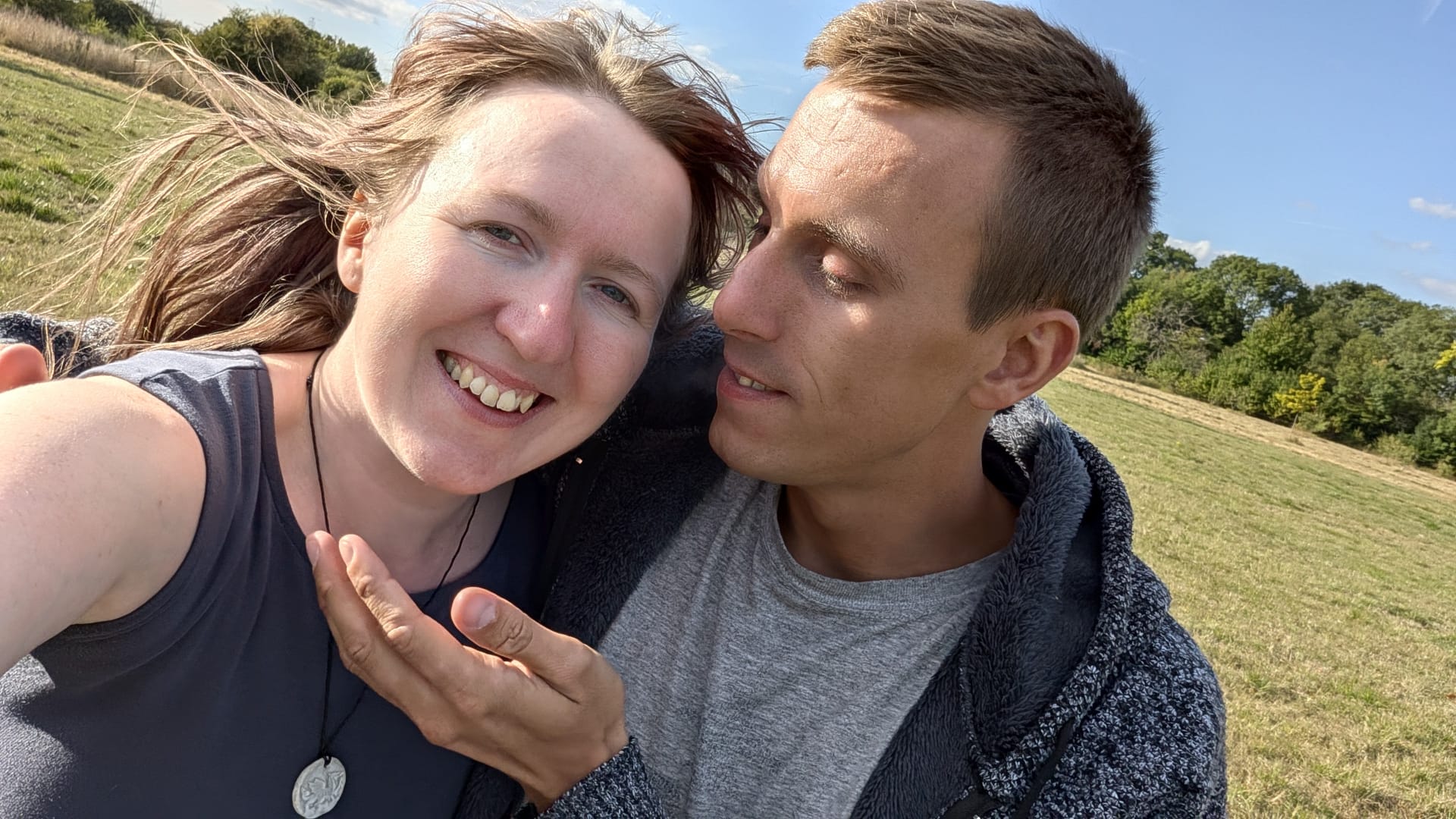 Hunter and his partner Erin together in a sunlit field, both smiling