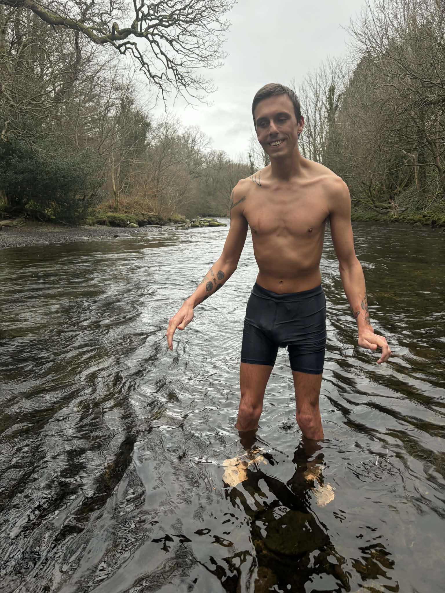 Hunter standing in the Afon Ogwen in winter, ankle deep in the current, smiling