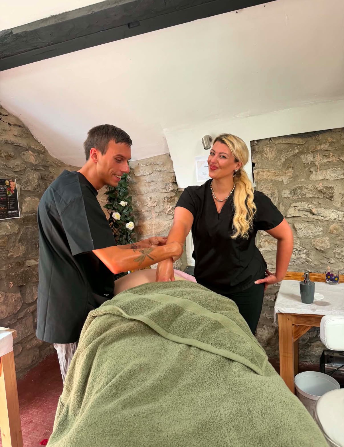Hunter working alongside a fellow trainee massage therapist, practicing full body technique on a client